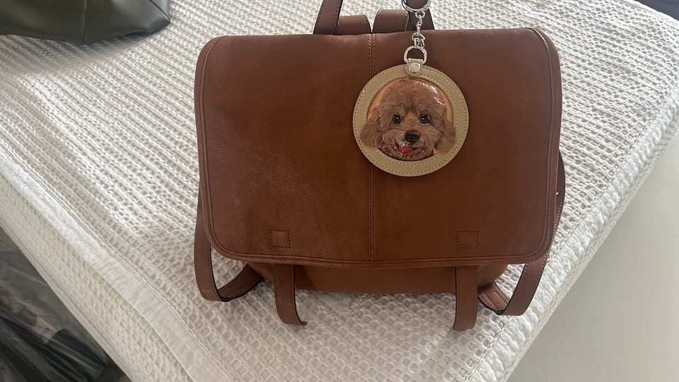 Pomeranian portrait keychain clipped to a brown leather work briefcase