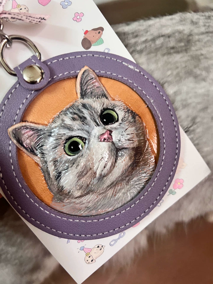 Customer holding tabby cat hand-tooled leather keychain on a card with paw prints
