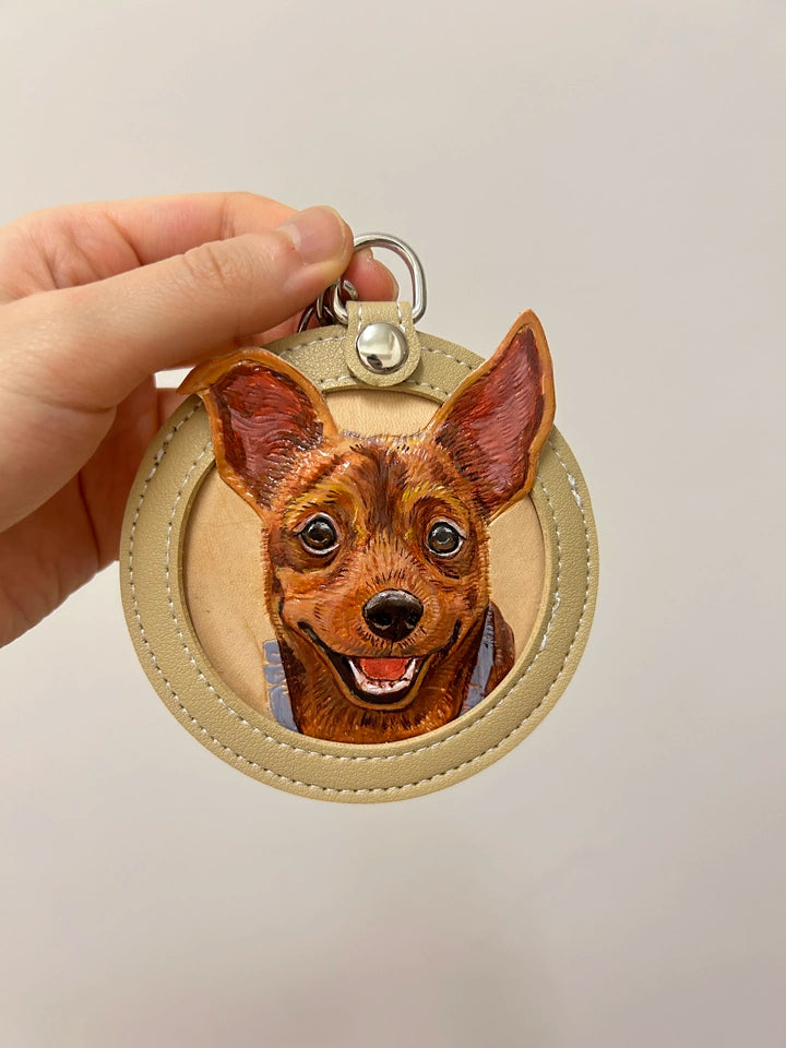Brown chihuahua portrait on almond leather keychain held close in soft light